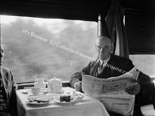 BUFFET CAR PASSENGERS AT TABLE READING THE CORK EXAMINER